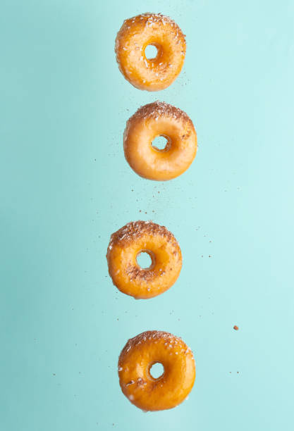istock Various decorated donuts in motion falling on a blue background. Sweet and iced donuts fall or fly in motion. With pieces of chocolate. Vertical photo. Light and tender photo. 1223347610