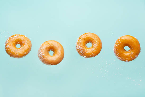 istock Falling donuts with coconut flakes on a light blue background. Freezing in motion, horizontal photo 1223348278