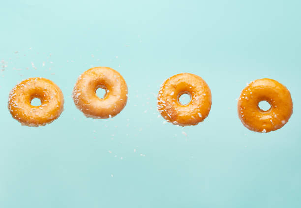istock Falling donuts with coconut flakes on a light blue background. Freezing in motion, horizontal photo 1223348369