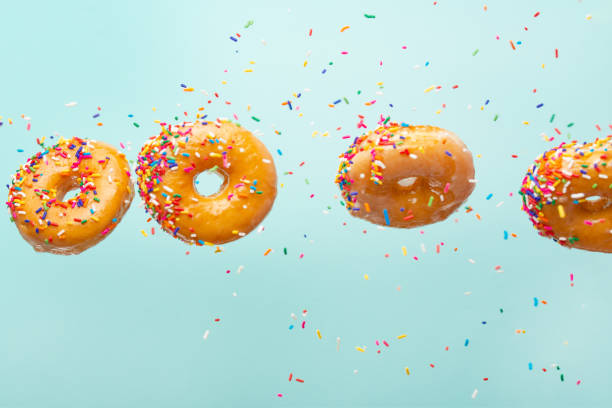 istock Various decorated donuts in motion falling on a blue background. Sweet and iced donuts fall or fly in motion. With caramel. Horizontal photo 1223348488