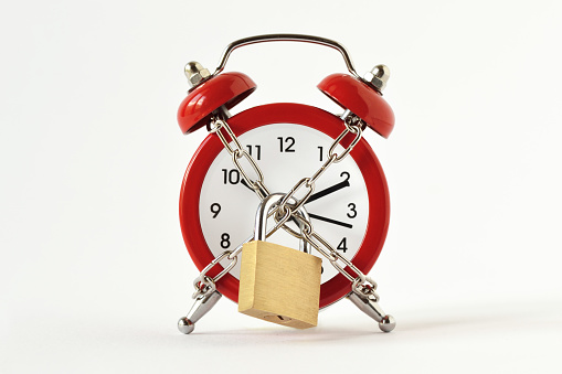 Alarm clock with chain and padlock on white background - Concept of time