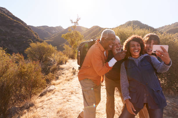 gruppo di amici anziani in posa per selfie mentre camminano lungo il sentiero in campagna insieme - retirement living foto e immagini stock