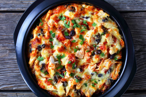 South american tamale pie of corn crust with tomato sauce, pulled chicken meat, cheddar cheese, black bean filling