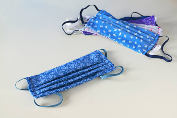 istock Sustainable washable masks for multiple use, homemade sewn from blue patterned cotton as protection against coronavirus pandemic on a gray background, copy space 1223353809