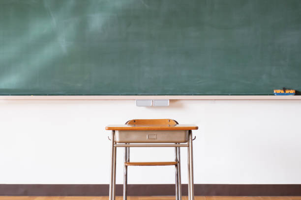 An image of a Japanese elementary school classroom with a blackboard and desk