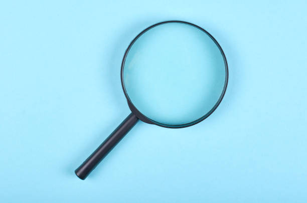 istock Black magnifying glass on blue background. 1223359009