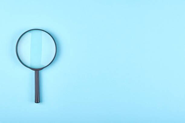 istock Black magnifying glass on blue background. 1223359030
