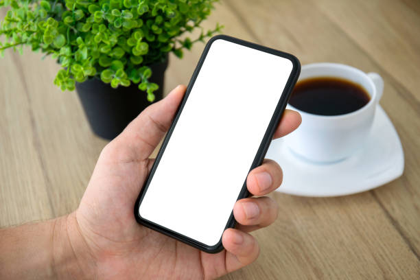 istock male hand holding phone isolated screen over table in cafe 1223360642