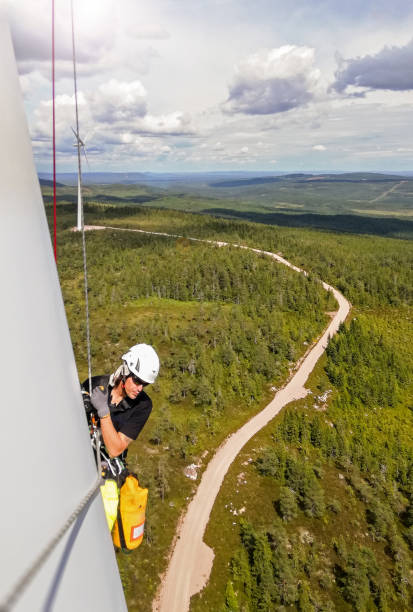 istock Professional rope access technicians doing inspection high up on blade of wind turbine in Sweden and forest and path is behind 1223361432