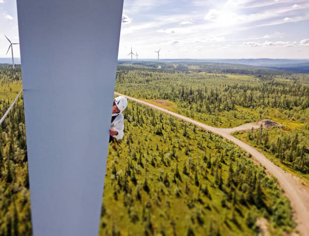 istock Professional rope access technicians doing inspection high up on blade of wind turbine in Sweden and forest, road and wind farm is behind 1223361517
