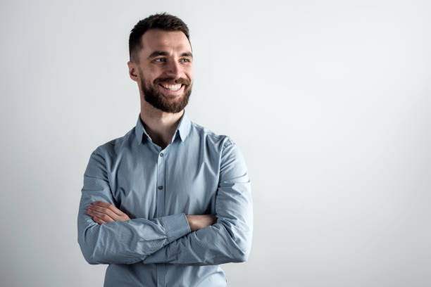 istock Cheerful guy in blue shirt stands folded hands and posing against a white studio background 1223361533