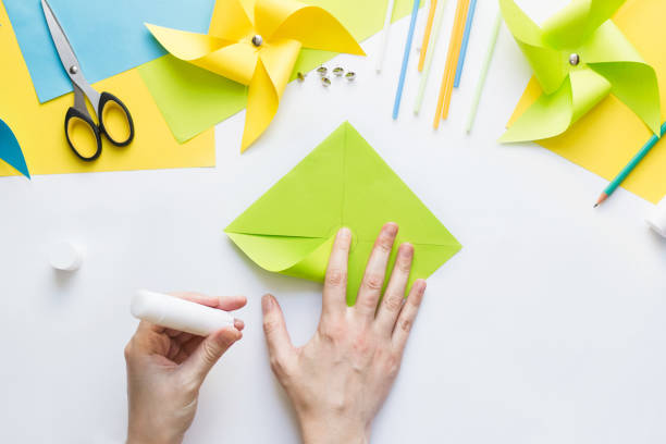 istock How to make paper green windmill toy with children at home. Step by step instructions. Hands making DIY summer project. Top view. Step 7. Glue corner in center of drawn circle. 1223364344