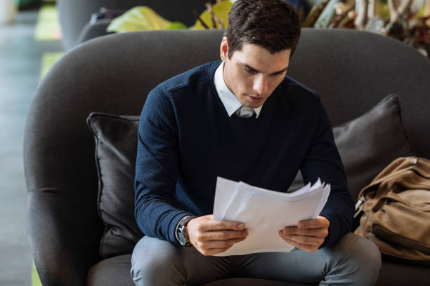 istock Elegant Young Businessman Reading Documents at a Cafe 1223367660