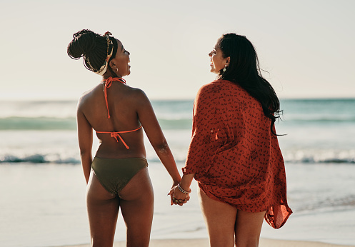 Cropped shot of attractive young friends standing together and holding hands while on the beach
