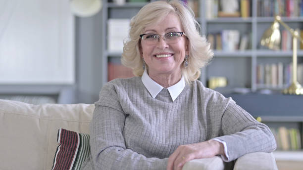 Gorgeous Old Woman Sitting on Sofa and Smiling at the Camera