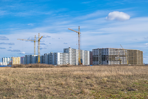 Panorama of multi-storey and multi-apartment residential buildings under construction on an abandoned agricultural field