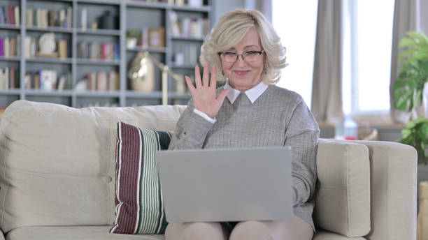 istock Old Woman Sitting on Sofa and doing Video Chat on Laptop 1223374018