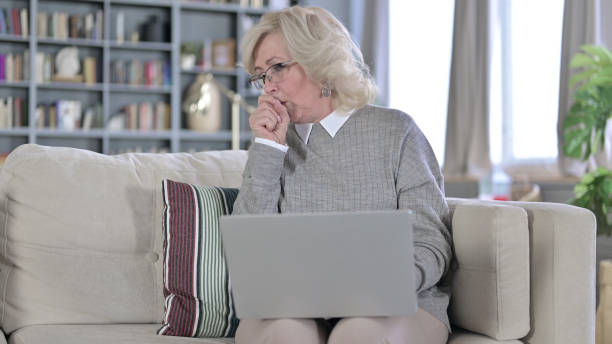 istock Sick Old Woman Working on Laptop and Coughing 1223374052