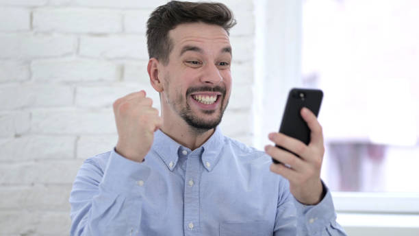 istock Young Man Celebrating Success on Smartphone 1223375165