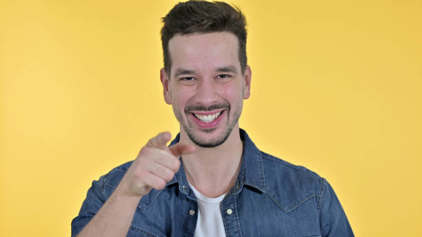 istock Attractive Young Man Pointing at Camera, Yellow Background 1223375882