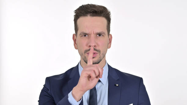 istock Attractive Young Businessman Putting Finger on Lips, White Background 1223376783