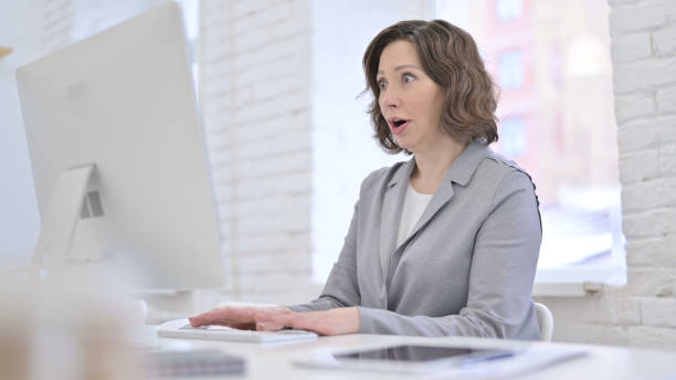istock Creative Old Woman Surprised by Results on Computer 1223377245