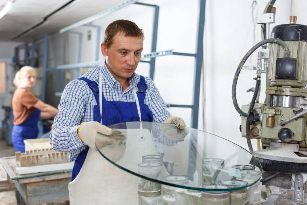 istock Man working on curved glass beveling machine 1223377254