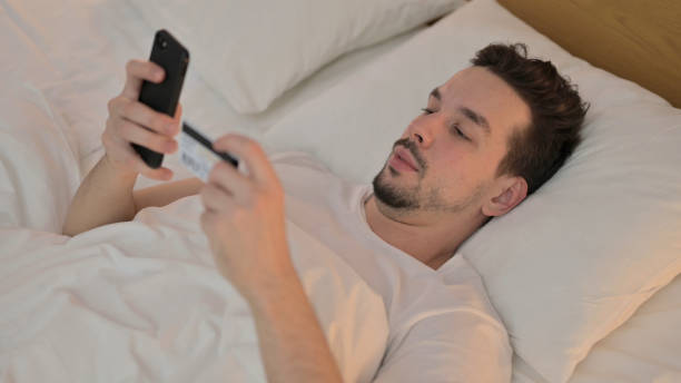 istock Online shopping by Young Man on Smartphone in Bed 1223377441