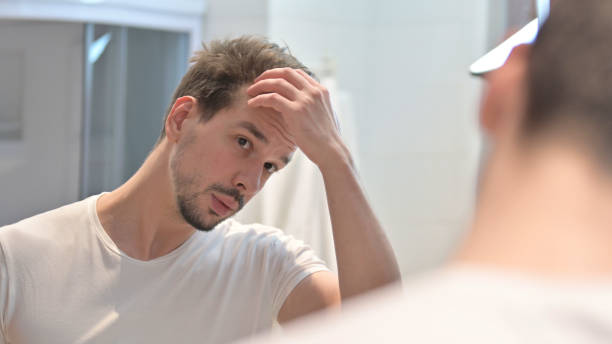 istock Young Man Fixing Hair in Mirror 1223377592