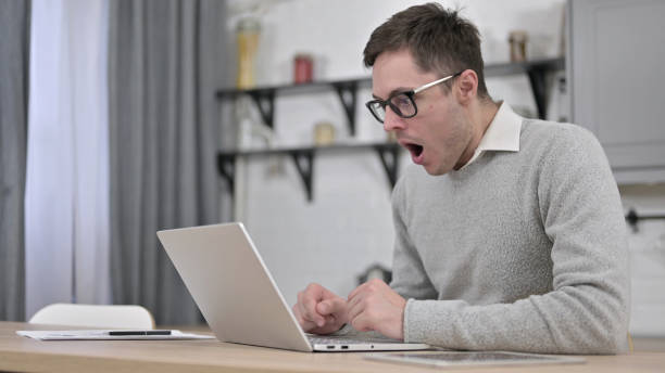 istock Young Man Shocked by Loss on Laptop 1223377871