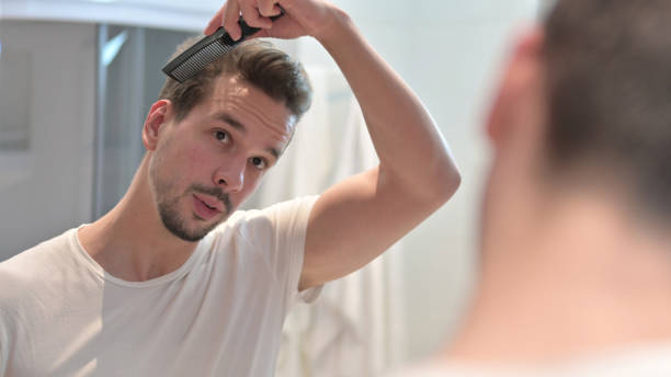 istock Young Man Combing Hair in Mirror 1223377915