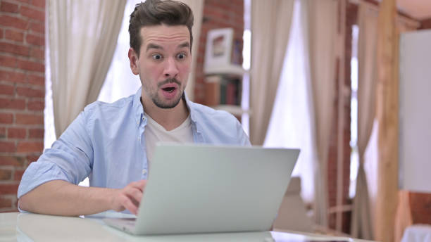 istock Upset Young Man Shocked by Results on Laptop 1223377918