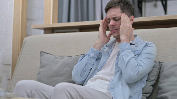istock Stressed Young Man having Headache in Living Room 1223378630
