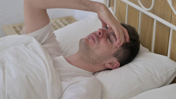 istock Tired Young Man Sleeping in Bed and having Headache 1223378650