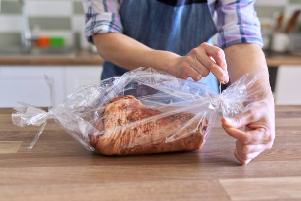 istock Woman packs pork leg marinated with spices in baking sleeve 1223378904