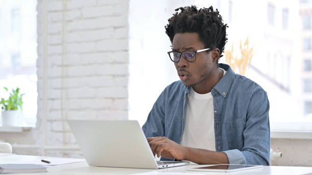 istock Young African Man get Surprise on Laptop in Office 1223380487