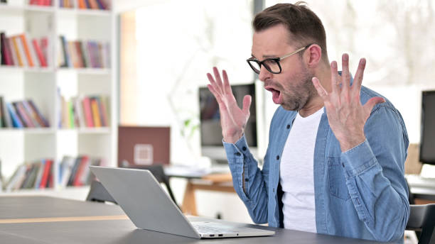 istock Young Man in Glasses Upset by Loss, Using Laptop 1223380592