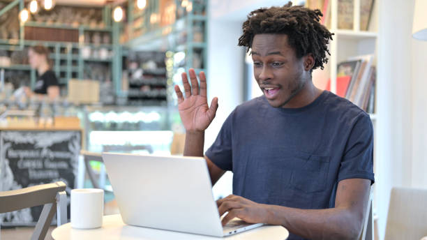 video chat su laptop di african man in cafe - 18602 foto e immagini stock