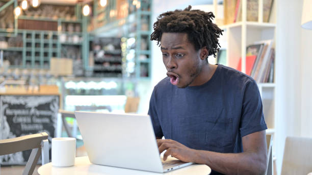 istock Shocked African Man Working on Laptop in Cafe 1223381606