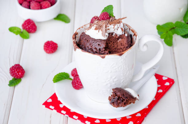 istock Chocolate mug cupcake with whipped cream, chocolate chips and fresh raspberries on a white wooden background. 1223383698