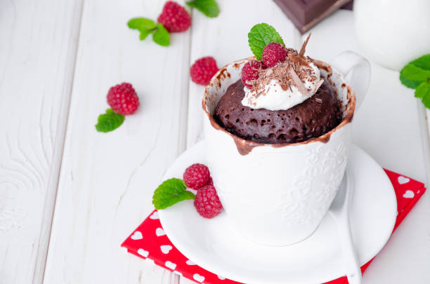 istock Chocolate mug cupcake with whipped cream, chocolate chips and fresh raspberries on a white wooden background. 1223383712