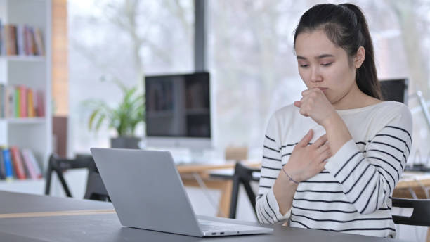 istock Coughing Young Asian Woman using Laptop in Cafe 1223385820