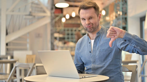 istock Casual Man with Laptop doing Thumbs down in Cafe 1223386288