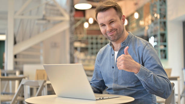 istock Casual Man with Laptop doing Thumbs Up in Cafe 1223386909