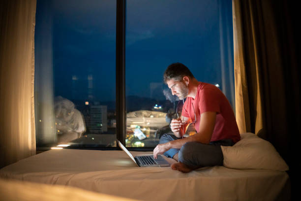 istock Guy sits on the bed and reads the content on his laptop 1223389401