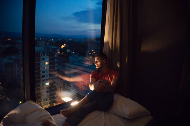 istock Man relaxes by the window looking at the view at night 1223389514