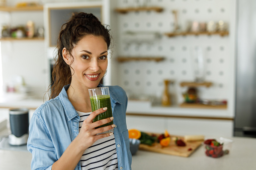 Female holding glass of green spinach detox smoothie