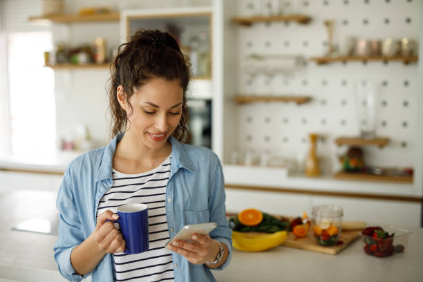 istock Young woman drinking first morning coffee and using smart phone 1223390834
