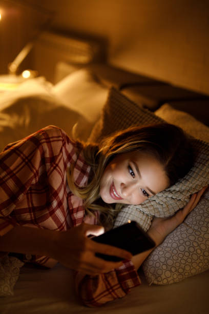 istock Beautiful young woman using mobile phone in bed at night 1223391210
