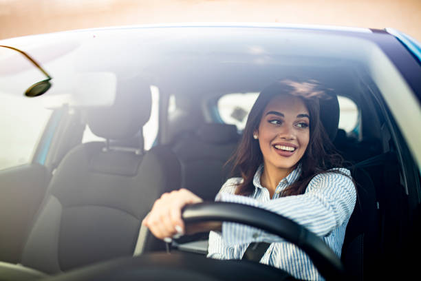 Cute young success happy brunette woman is driving a car. Happy woman driving a car and smiling. Cute young success happy brunette woman is driving a car. Portrait of happy female driver steering car with safety belt driving steering wheel stock pictures, royalty-free photos & images